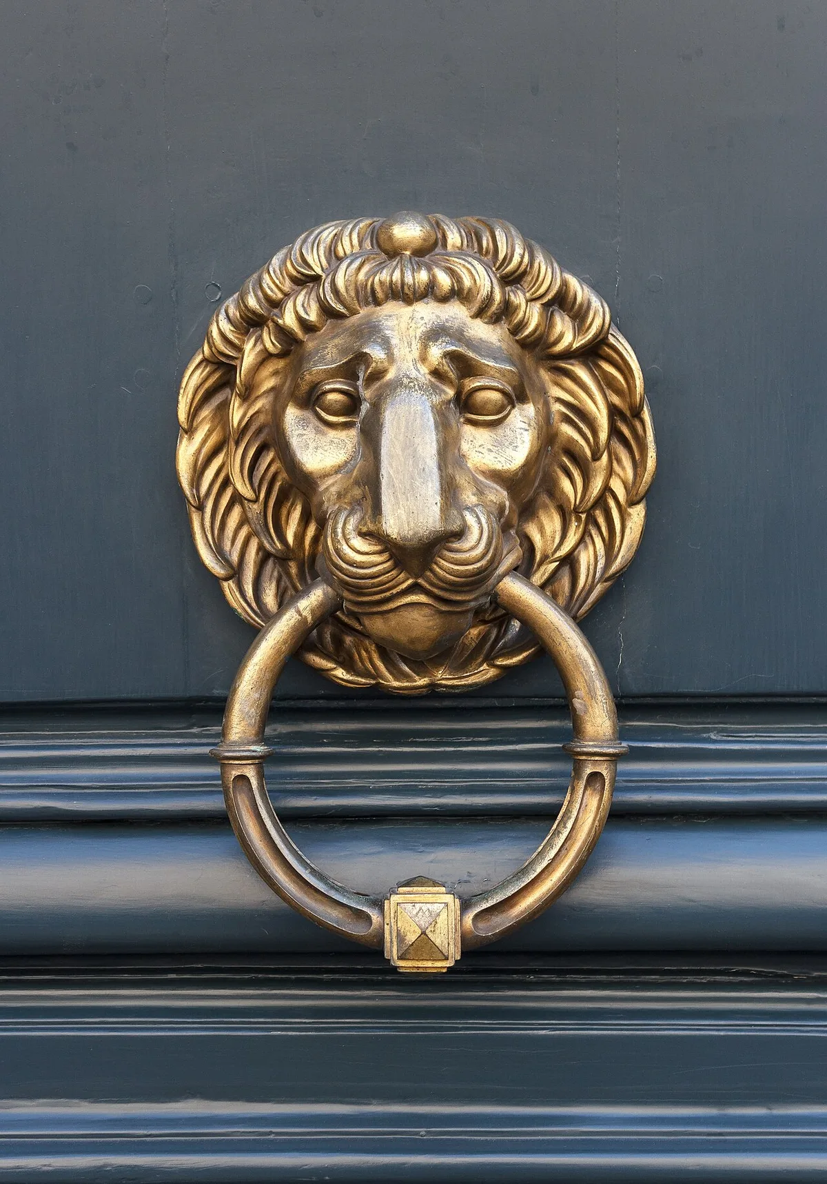 Goldener Löwenkopf-Türklopfer aus Messing an einer dunkelblauen Haustür