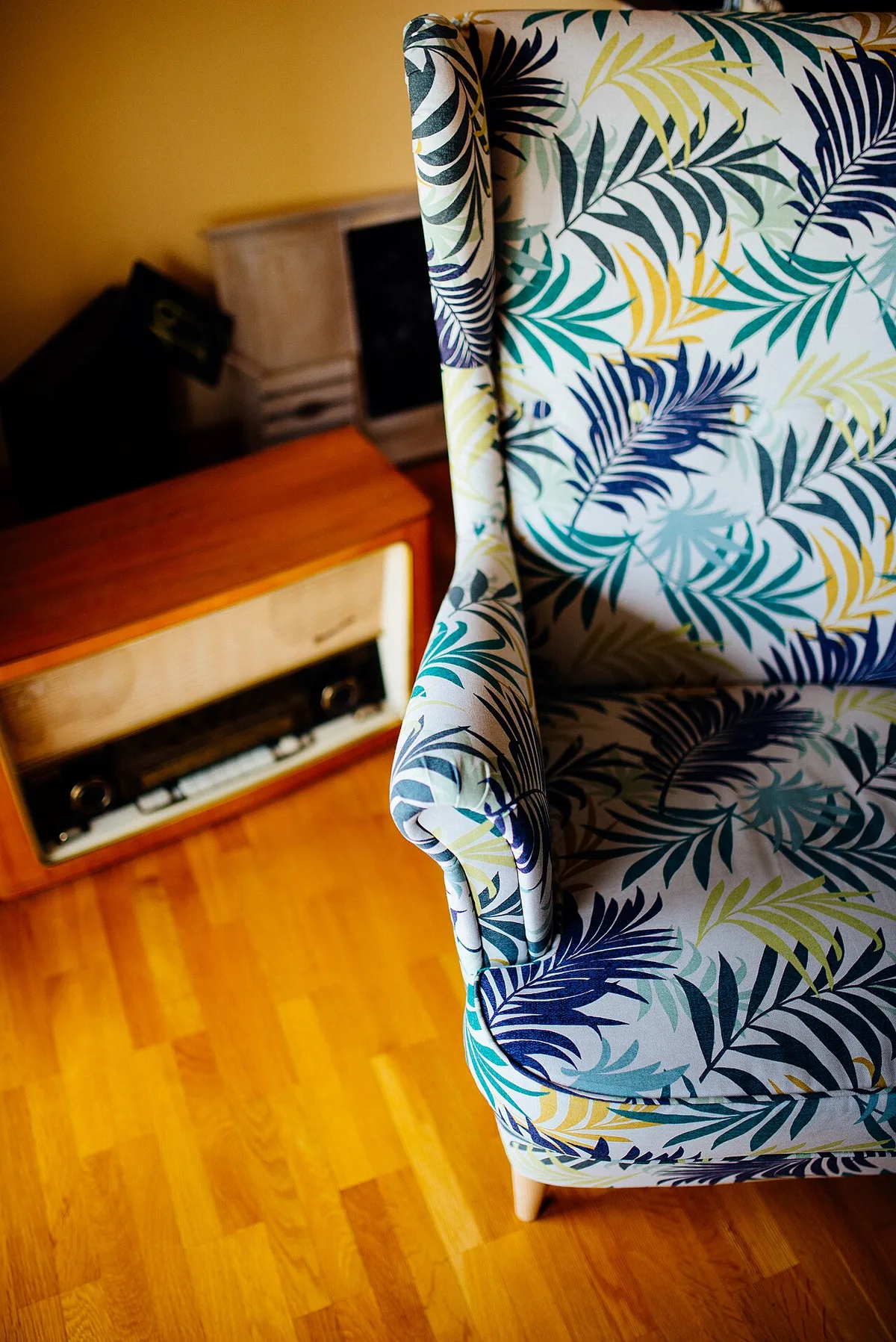 Bunt gemusterter Retro-Sessel neben einem alten Holzradio im Wohnzimmer